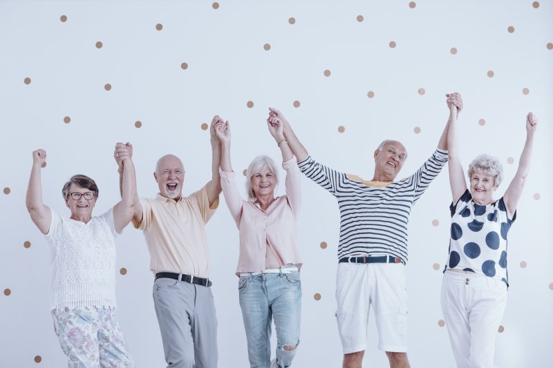 Group of happy seniors holding hands and jumping in the air